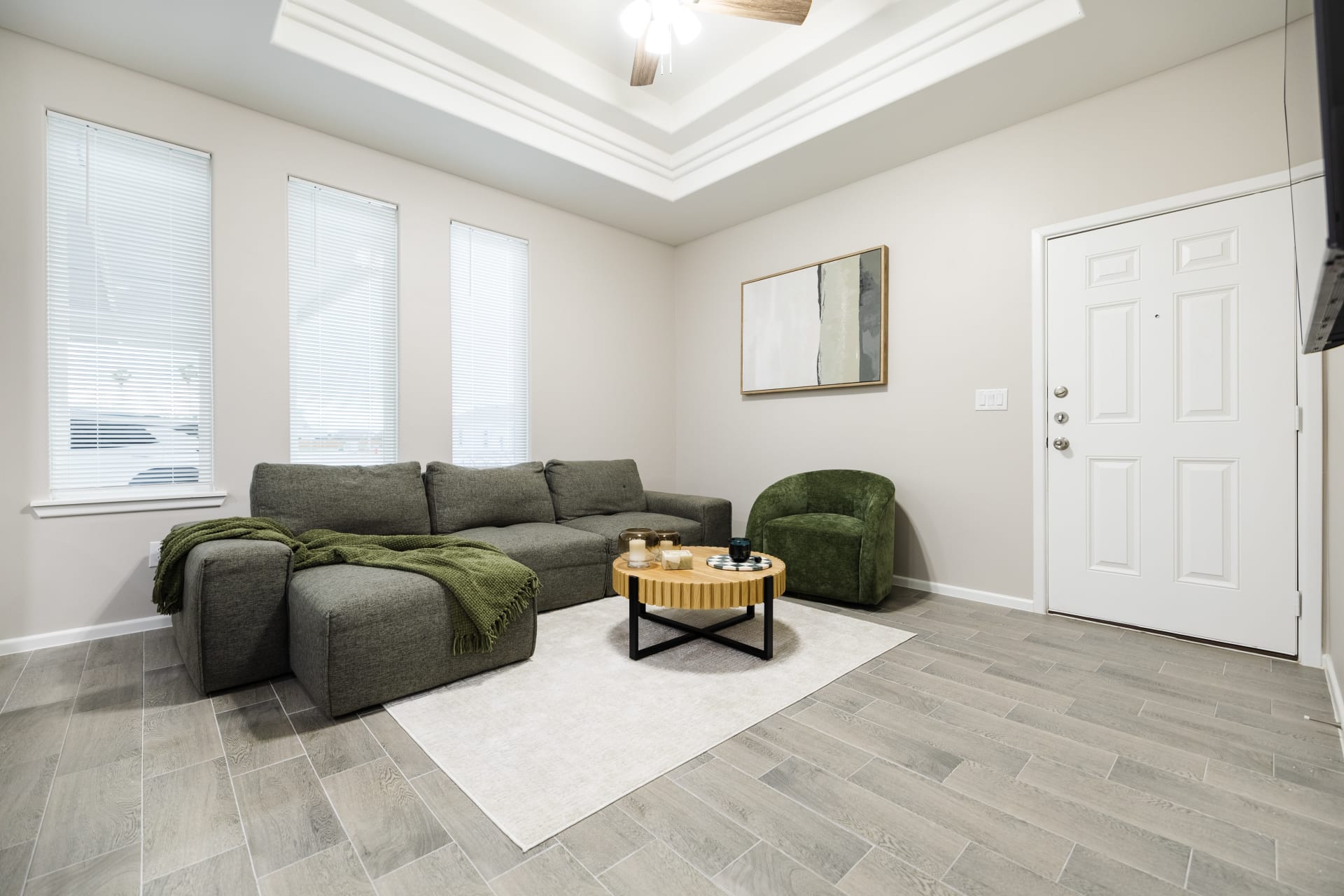 Staged living room with tray ceiling and tile flooring at Westwood Villas