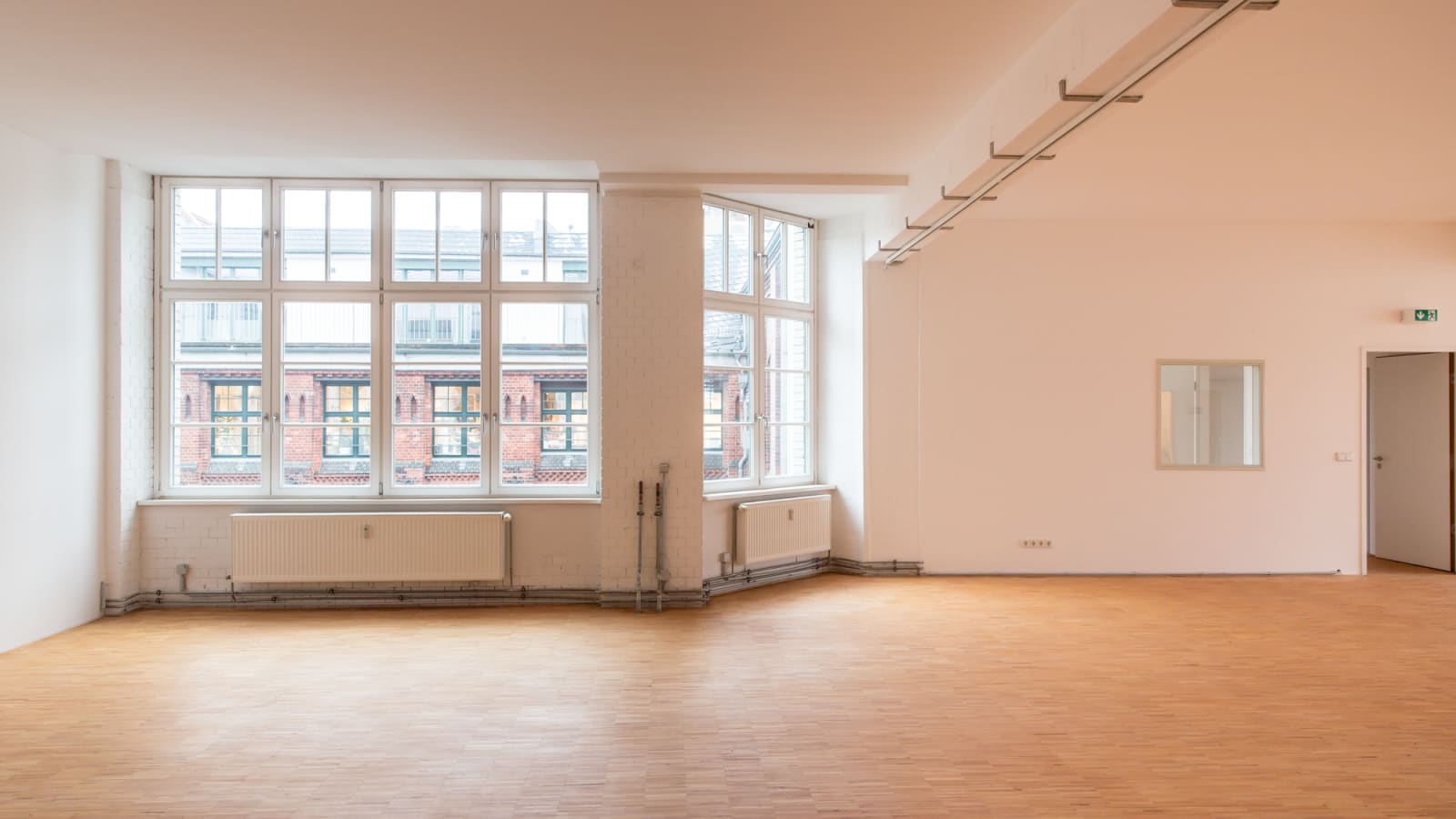 Vorher: leerer Loft mit Parkett und großen Fenstern