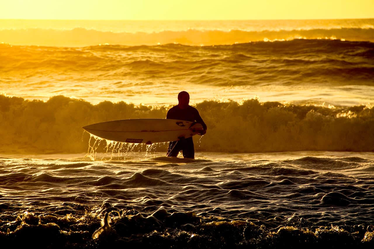 man in black wetsuit holding white surfboard on sea waves during daytime