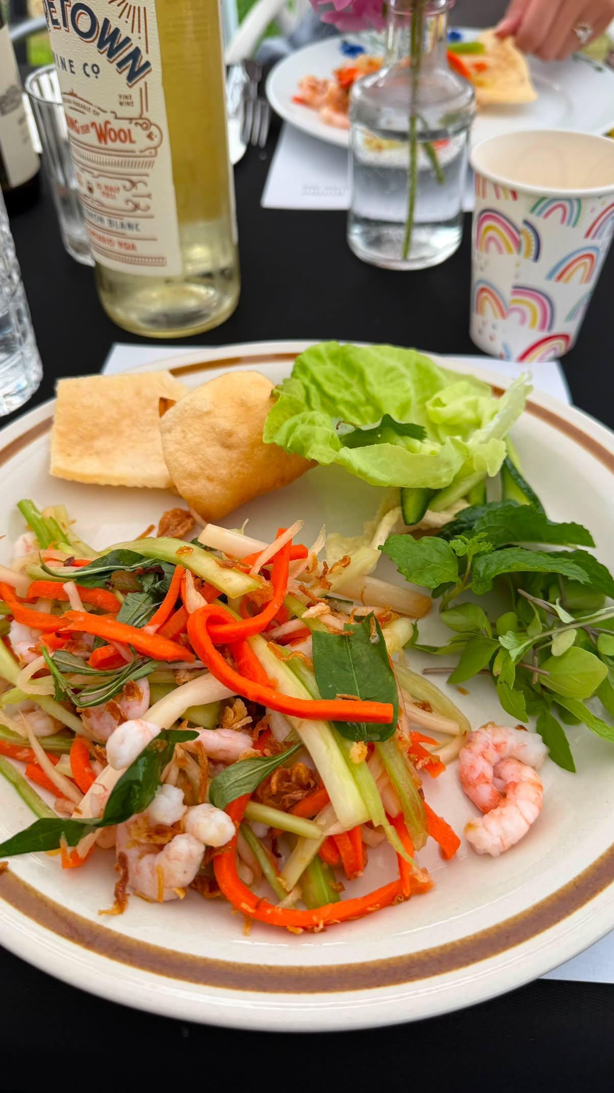 Salad, wine, and spring rolls on the table
