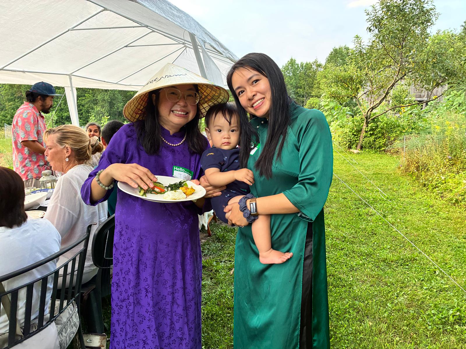 Two guests in ao dai smiling with a baby