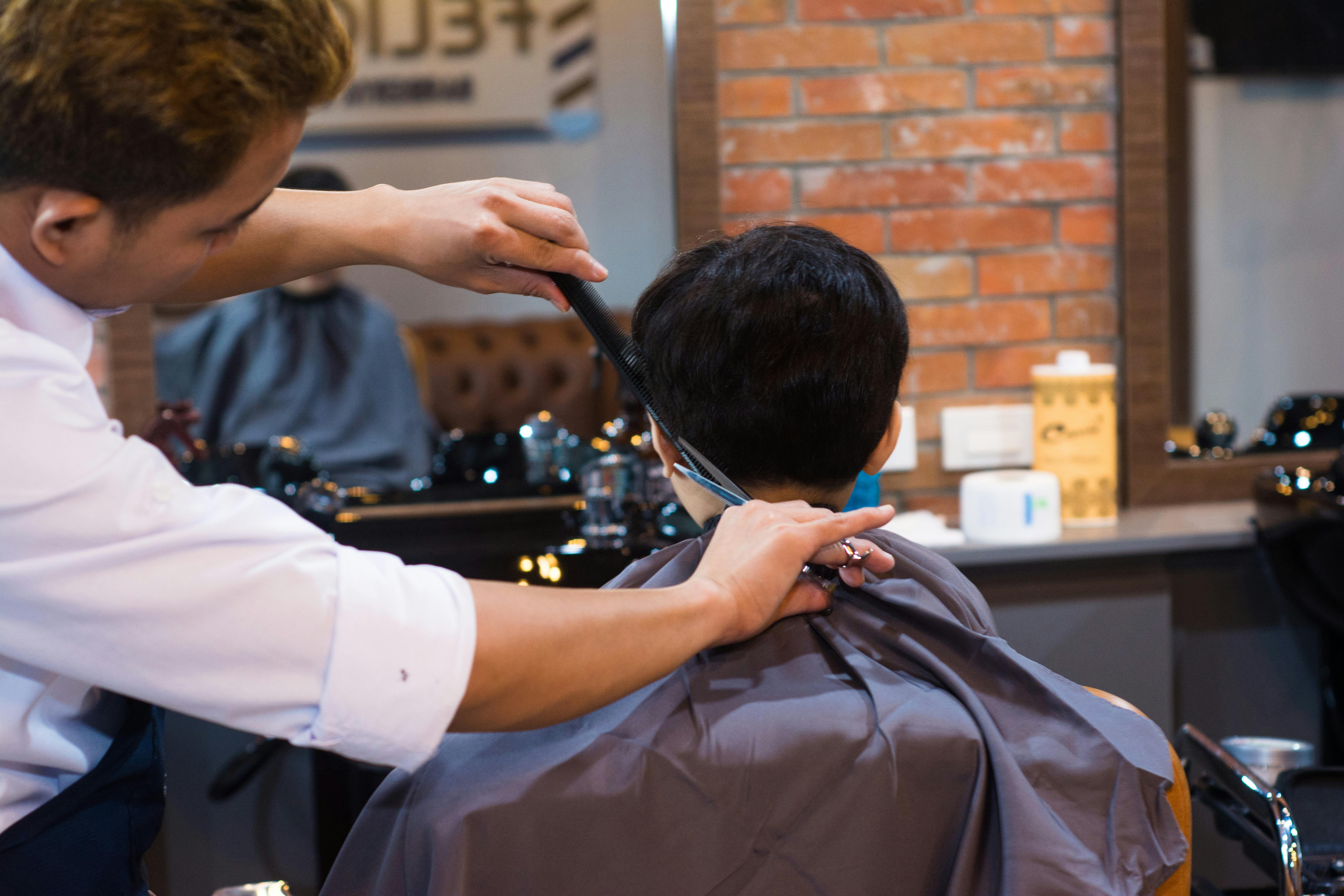 Image of barber cutting client"s hair in a saloon