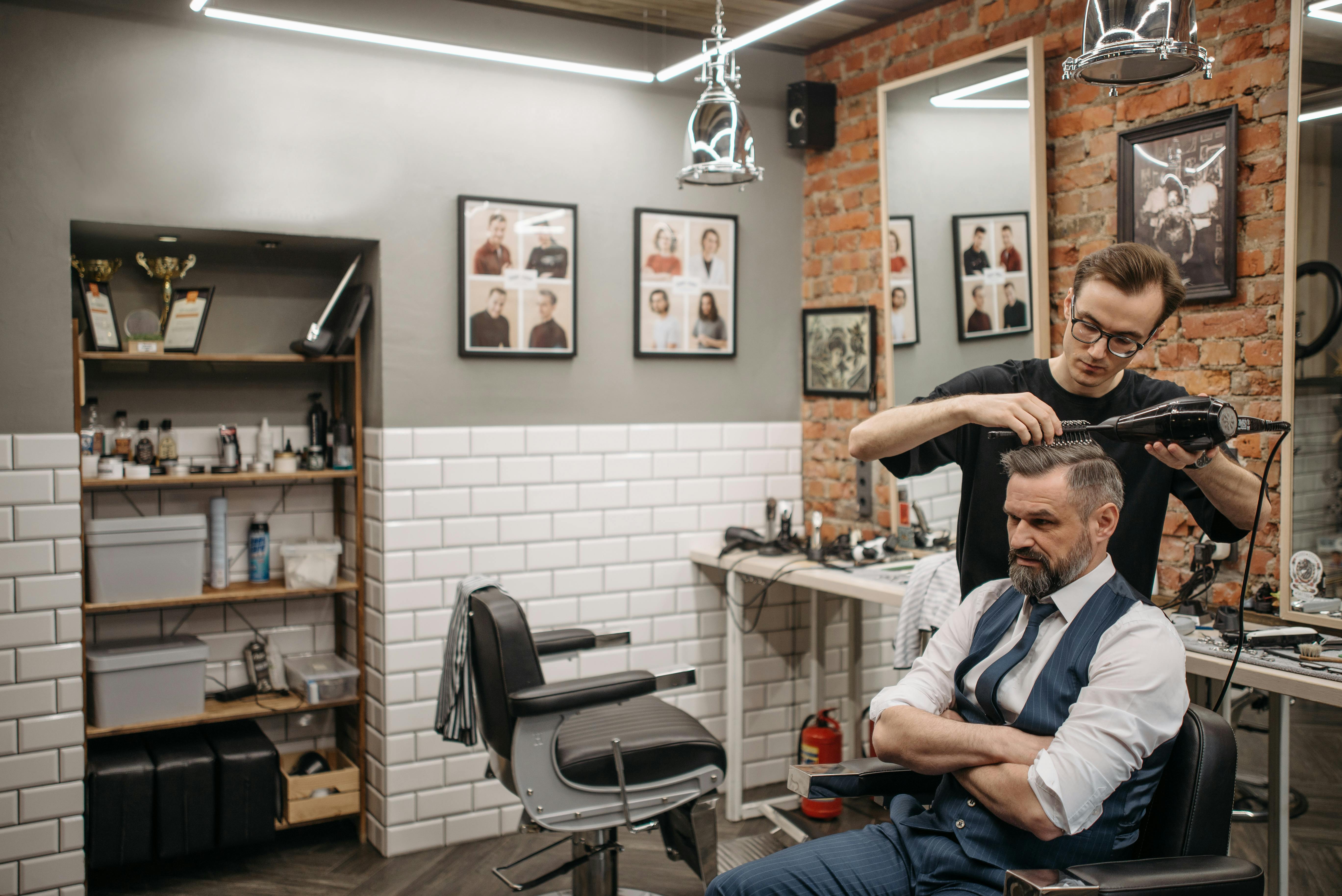 a barber doing man's hair grooming in barbershop in kellyville
