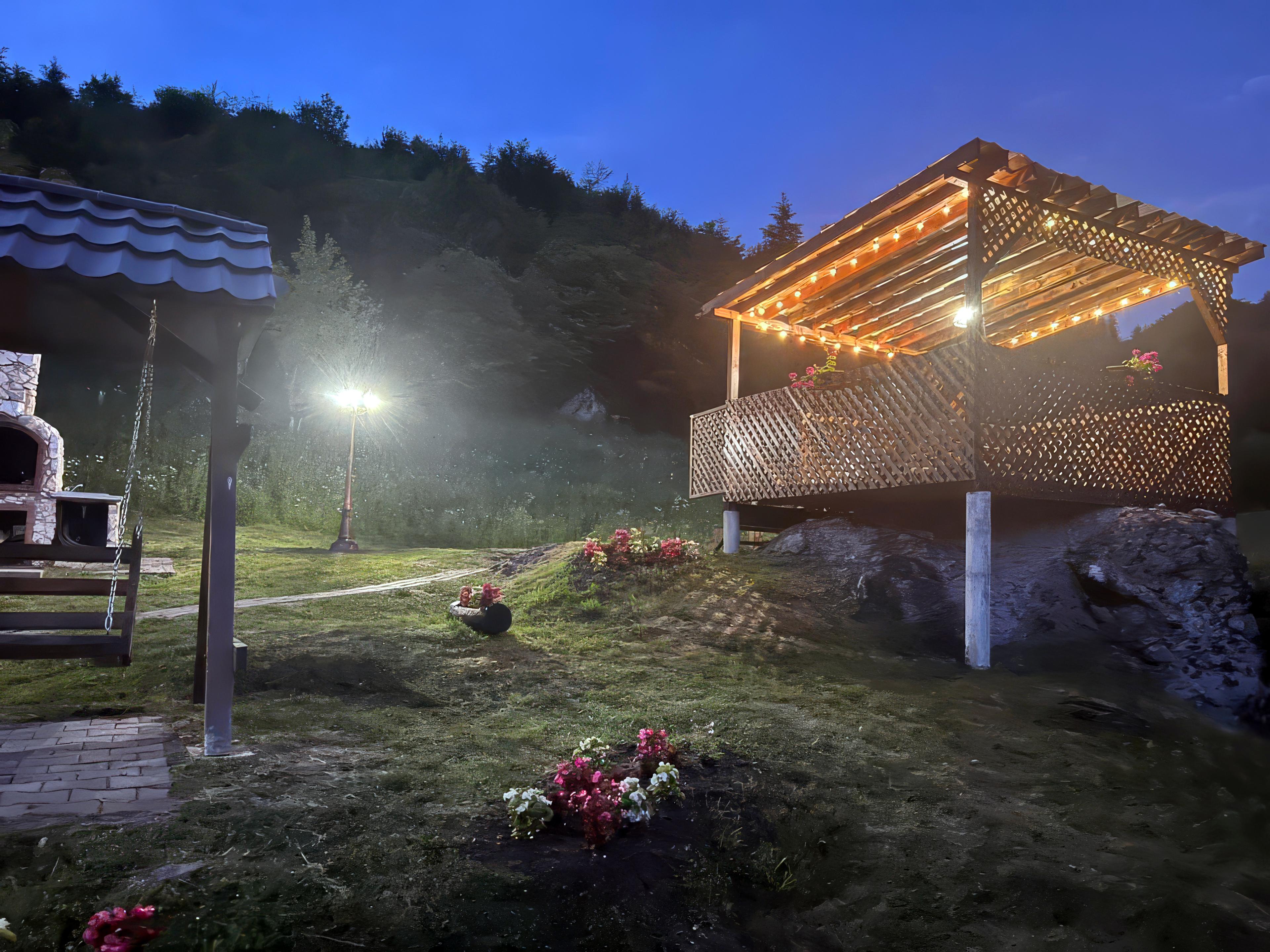 Pergolă din lemn și zonă de luat masa în aer liber cu grătar de piatră la Cabana Tăul Brazi, cabană montană, Roșia Montană, Apuseni