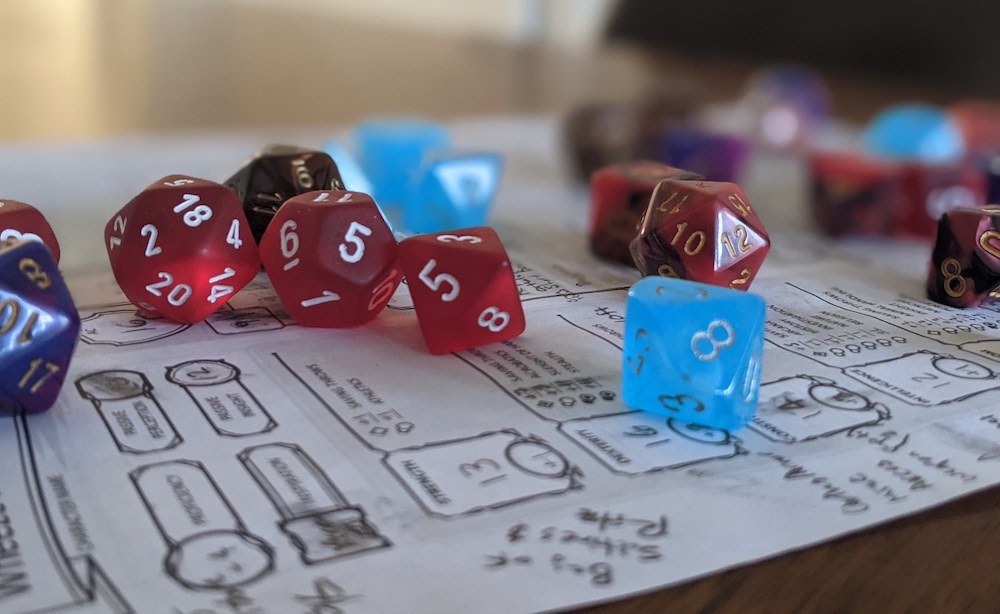 Multicolored dice are sitting on top of a dungeons and dragons character sheet.