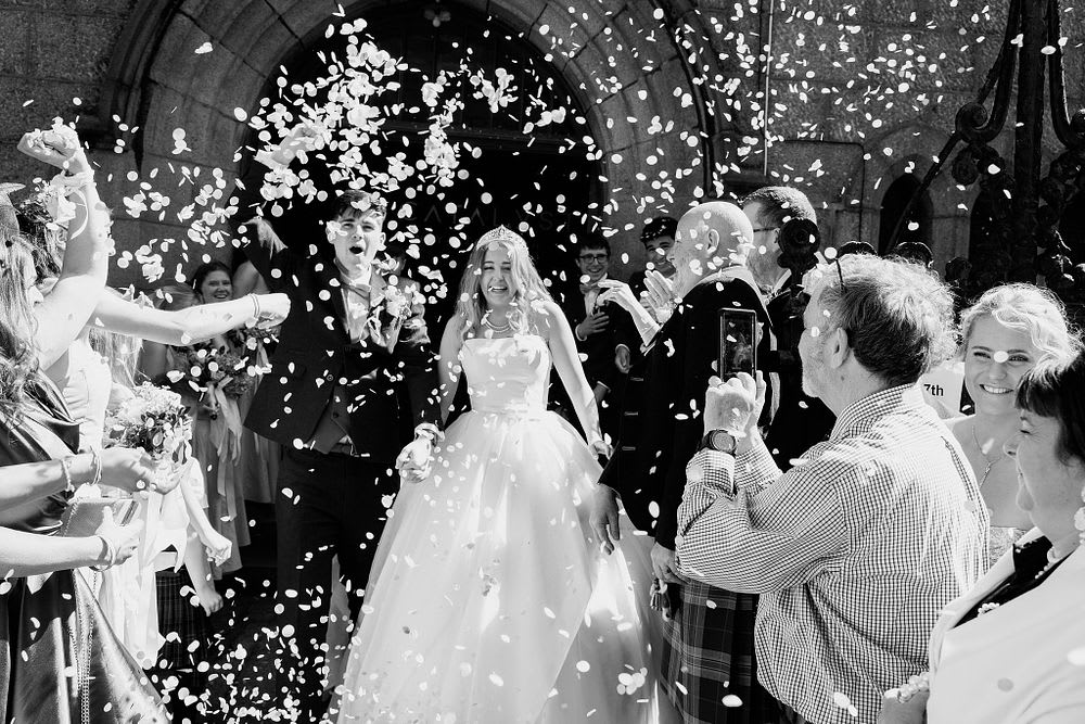 Confetti falls around India and Euan outside the church
