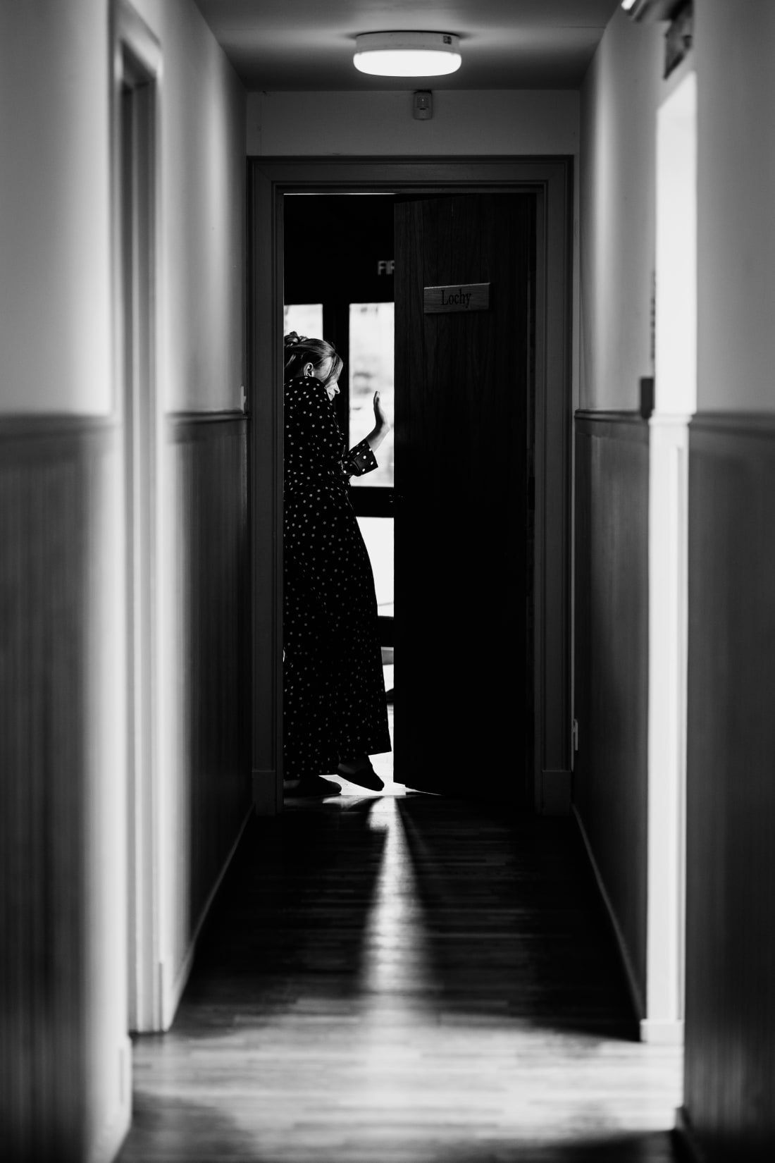 A figure waits at the end of a long, dark corridor