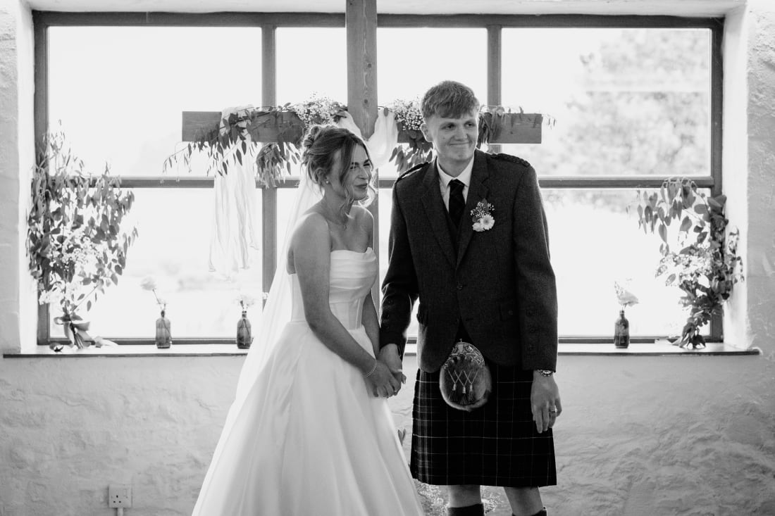 Ellie and Nathan hold hands in front of the barn windows