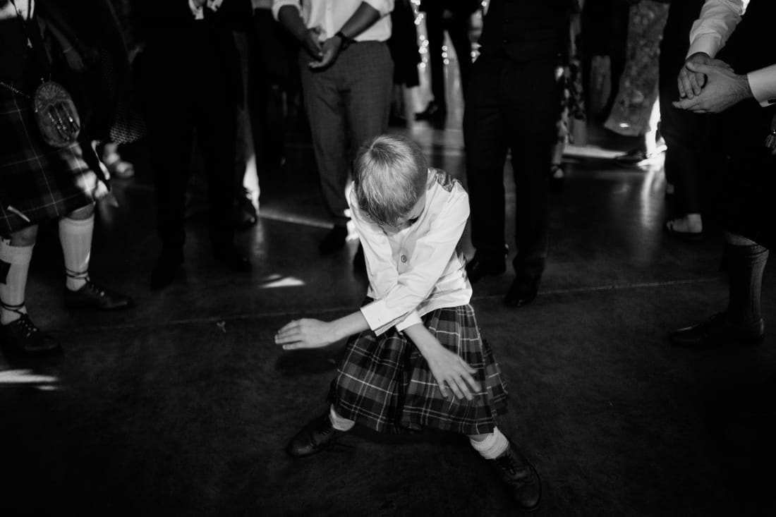 A young guest in a kilt dances on the dance floor