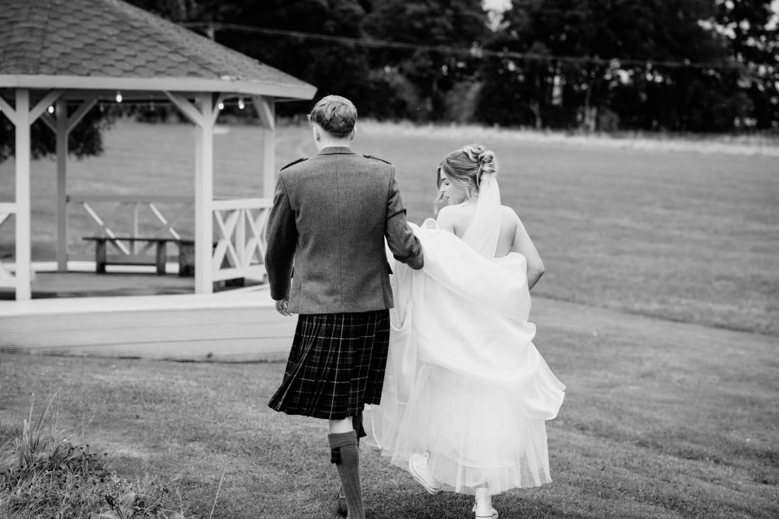 The couple walk across the lawn towards the gazebo