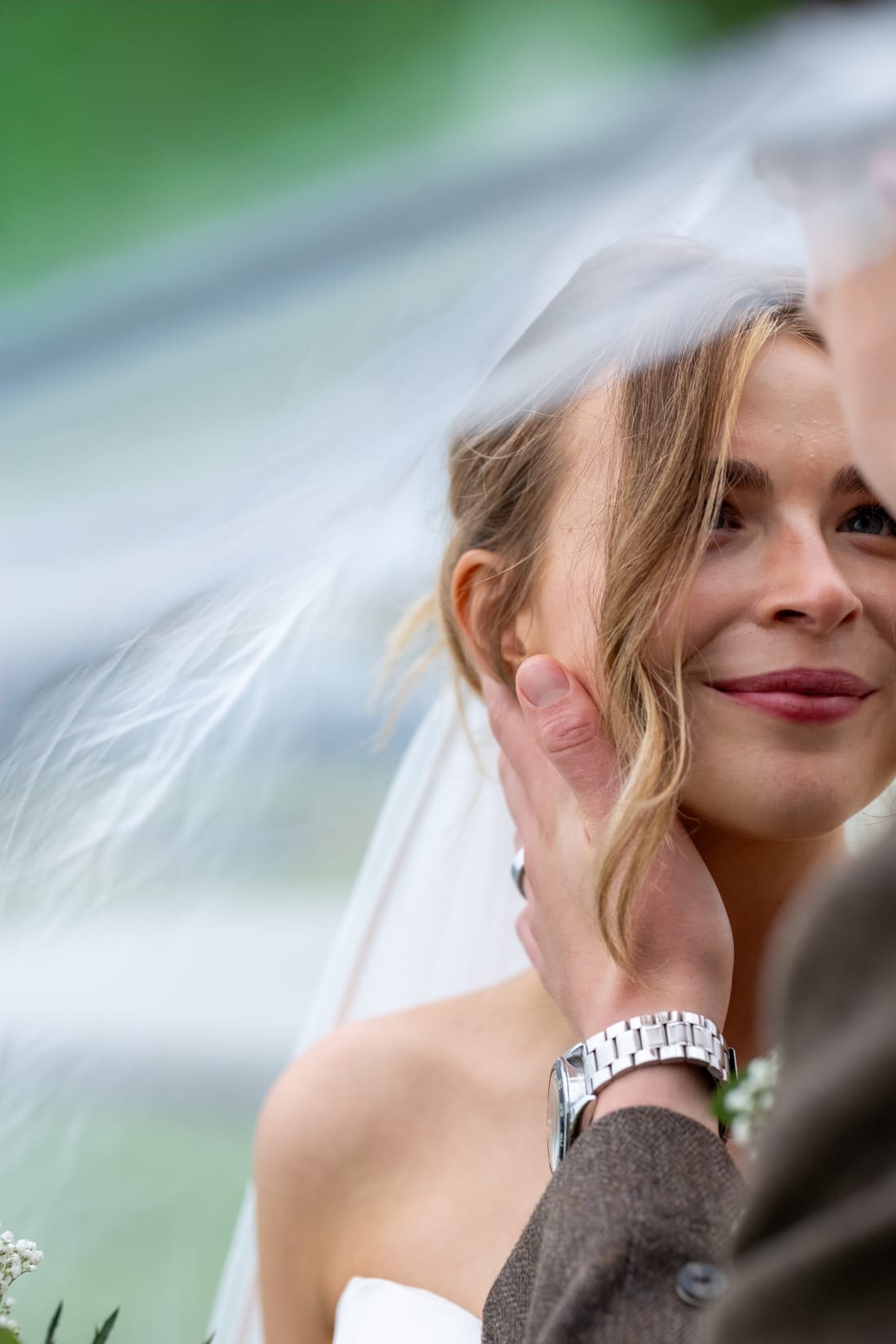 The bride smiles as her veil lifts in the wind