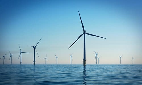 Decarbonising our electricity supply is one of the most important climate change actions. Image shows an offshore windfarm, consisting of two rows of wind turbines in a calm sea against a blue sky