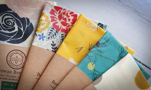 Take climate change action every day by changing to eco-friendly products. Image shows some of our favourite eco-friendly products - five brightly coloured beeswax wraps on a wooden table