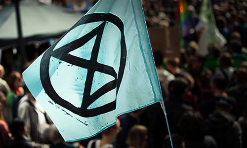 Climate change action - activism and community projects. Image shows an extinction rebellion flag at climate protest