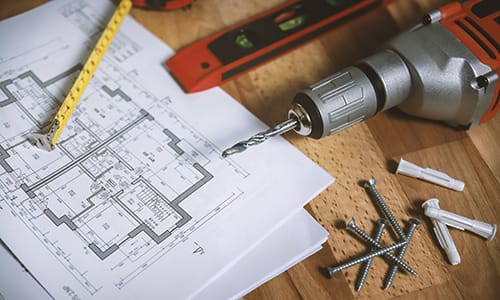 Climate change action - build better buildings. Image shows a construction plan with drill, screws, tape measure & spirit level