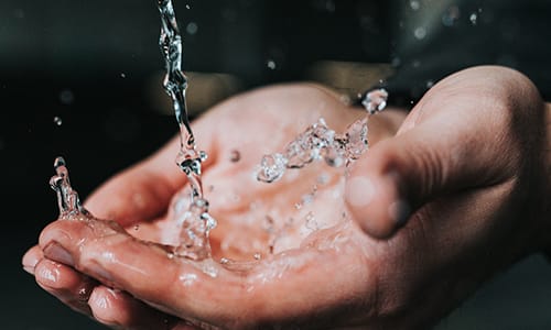 Climate change action - preserve and protect water. Image shows water splashing into hands