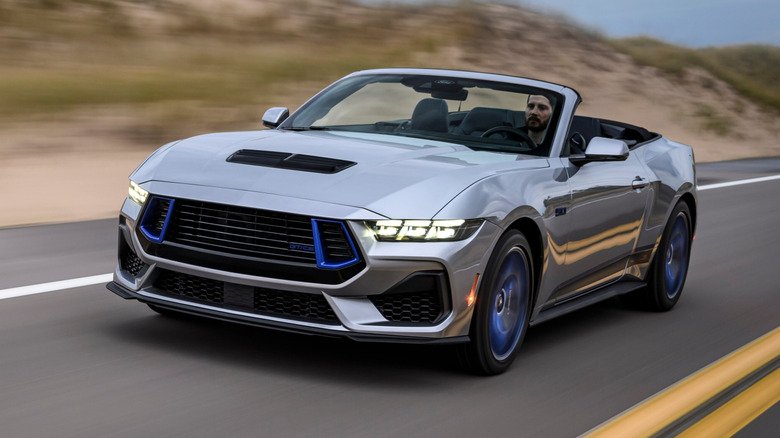 A silver and blue Ford Mustang California Special driving on a road. A silver and blue Ford Mustang California Special driving on a road.