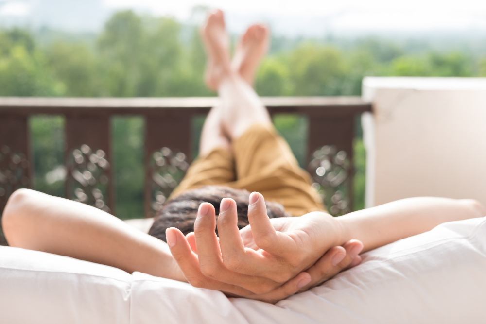 homme allongé sur un sofa dehors et qui semble totalement relaxé par sa position corporelle détendue