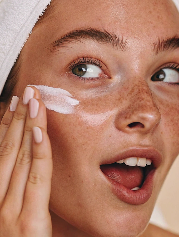 Modelo aplicándose crema, piel luminosa estilo K-Beauty