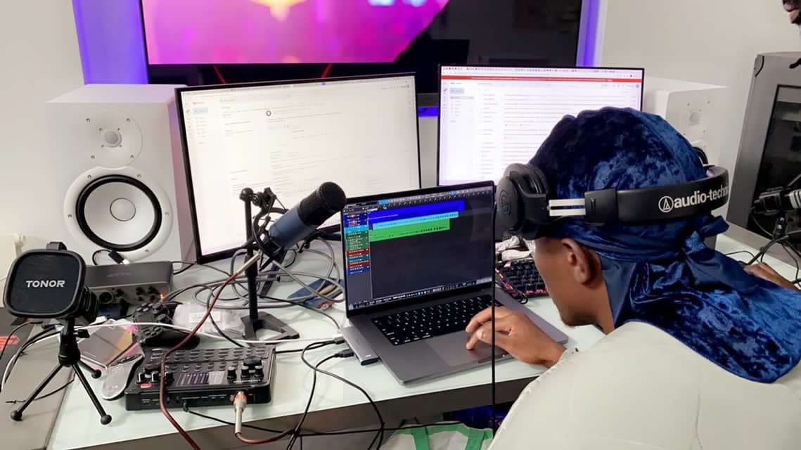 Kama in a blue velvet durag and headphones working the session at a mixing desk