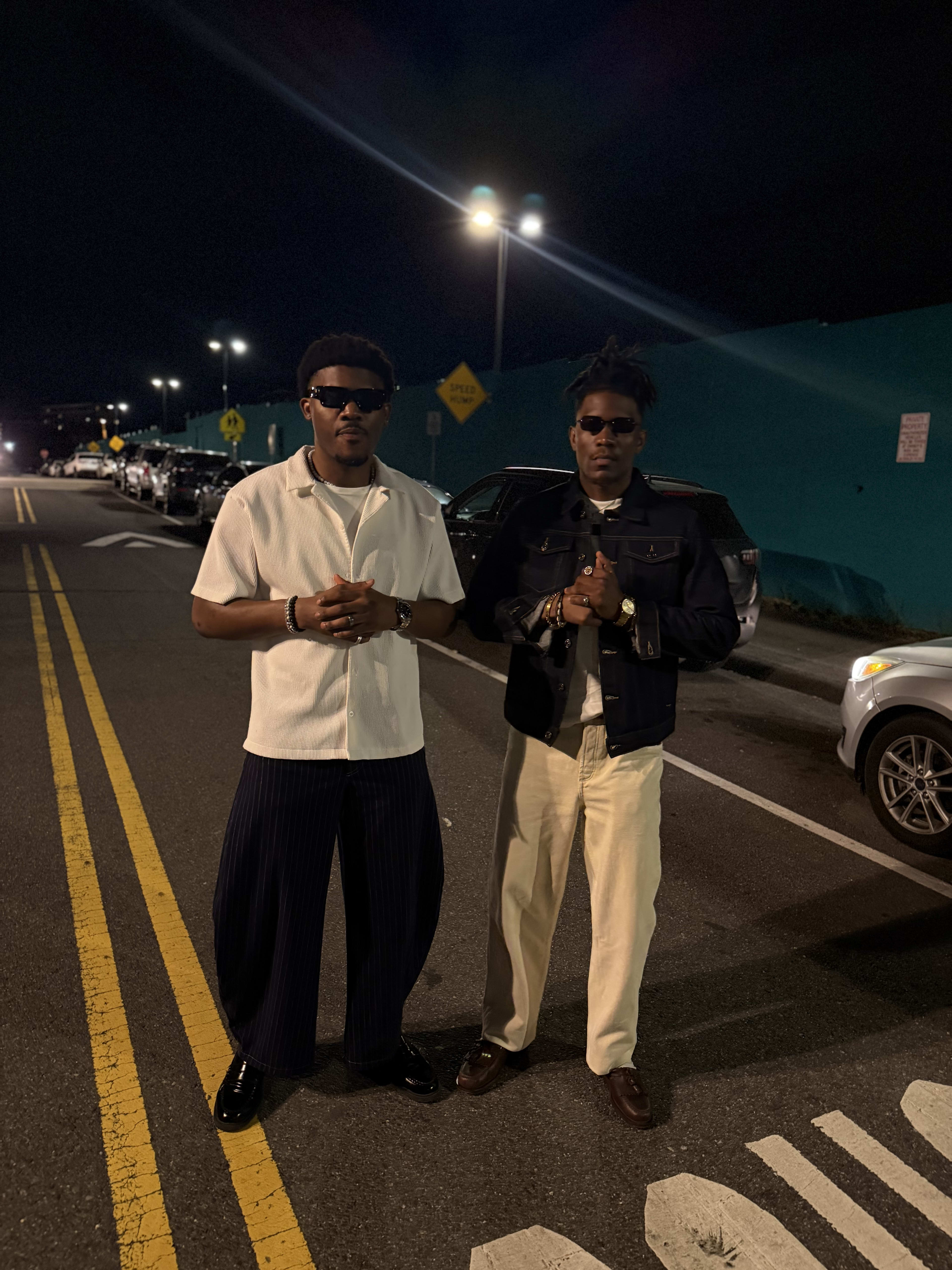 Kama and a friend straight-faced under the streetlights, hands clasped