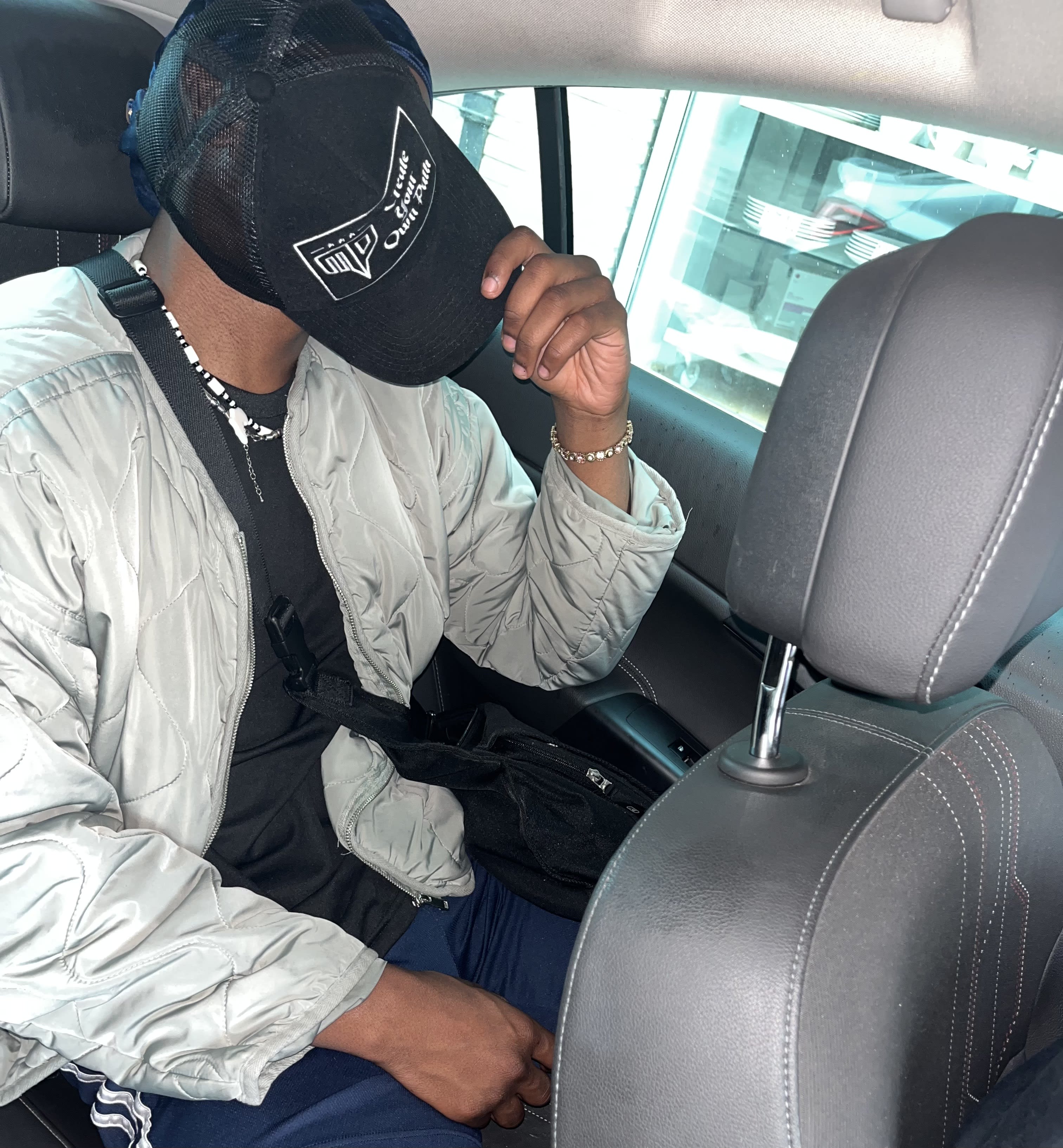 Back seat, brim pulled all the way down - quilted bomber and beaded chain, face hidden