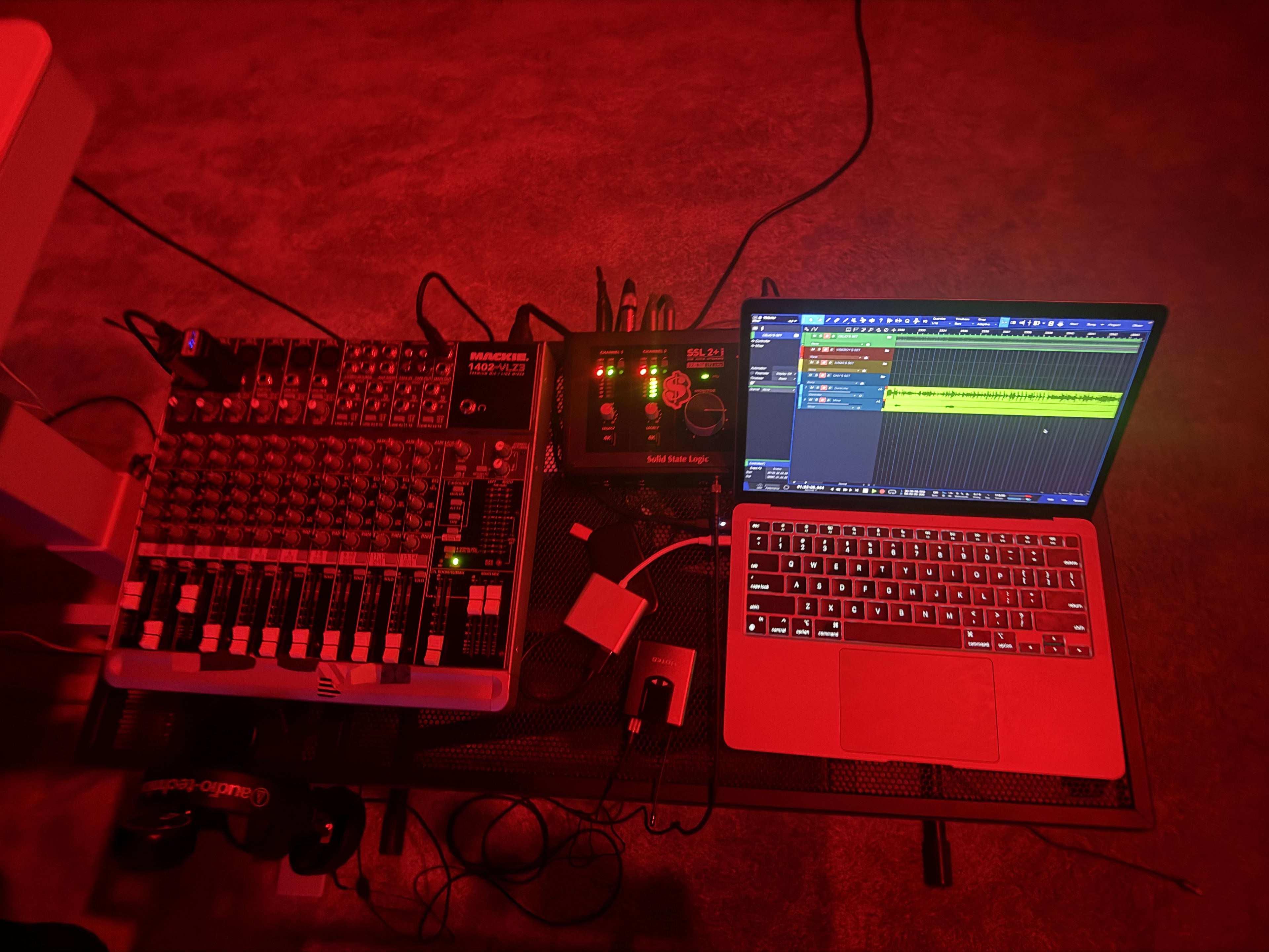 Red-lit mobile rig - mixer, interface, and laptop running the session on a folding stand
