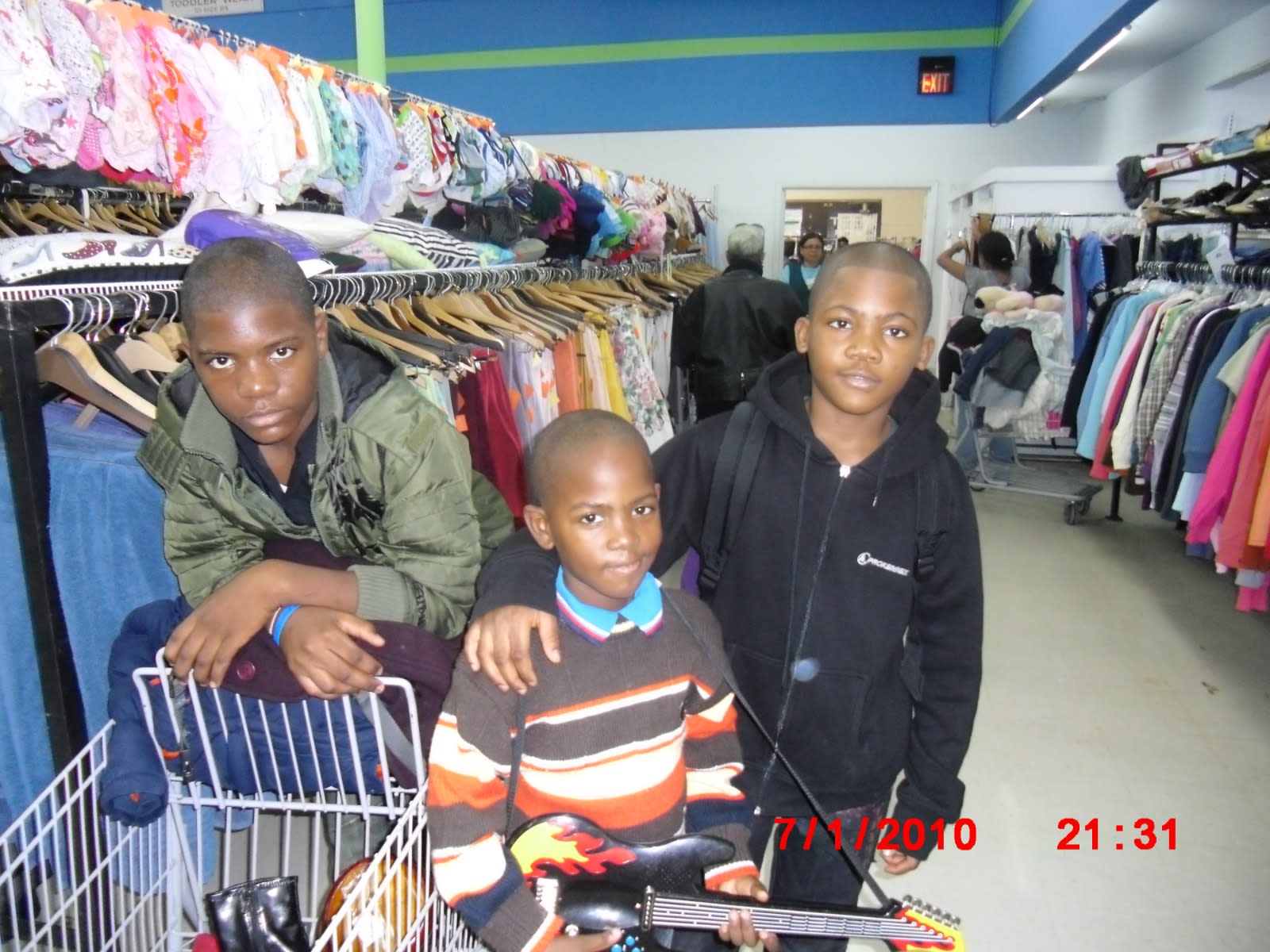 Childhood, July 2010: three brothers in a thrift store, the youngest holding a toy guitar