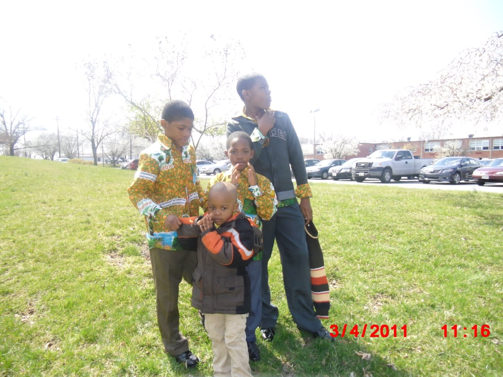 Childhood, 2011: four kids on a grassy hill, two in matching African-print shirts, blossoms out