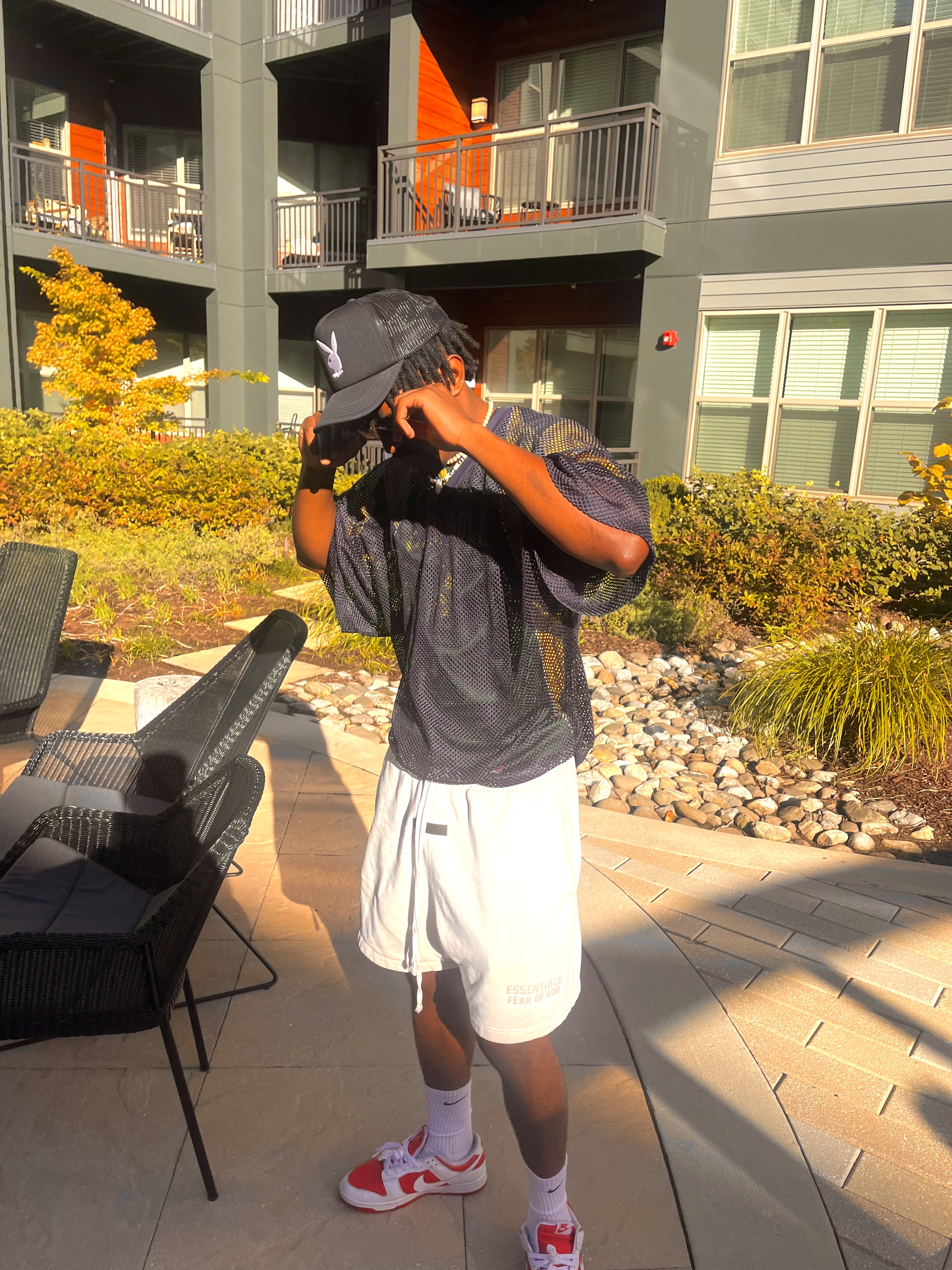 Golden hour in the courtyard - tipping the Playboy trucker cap, mesh jersey shining