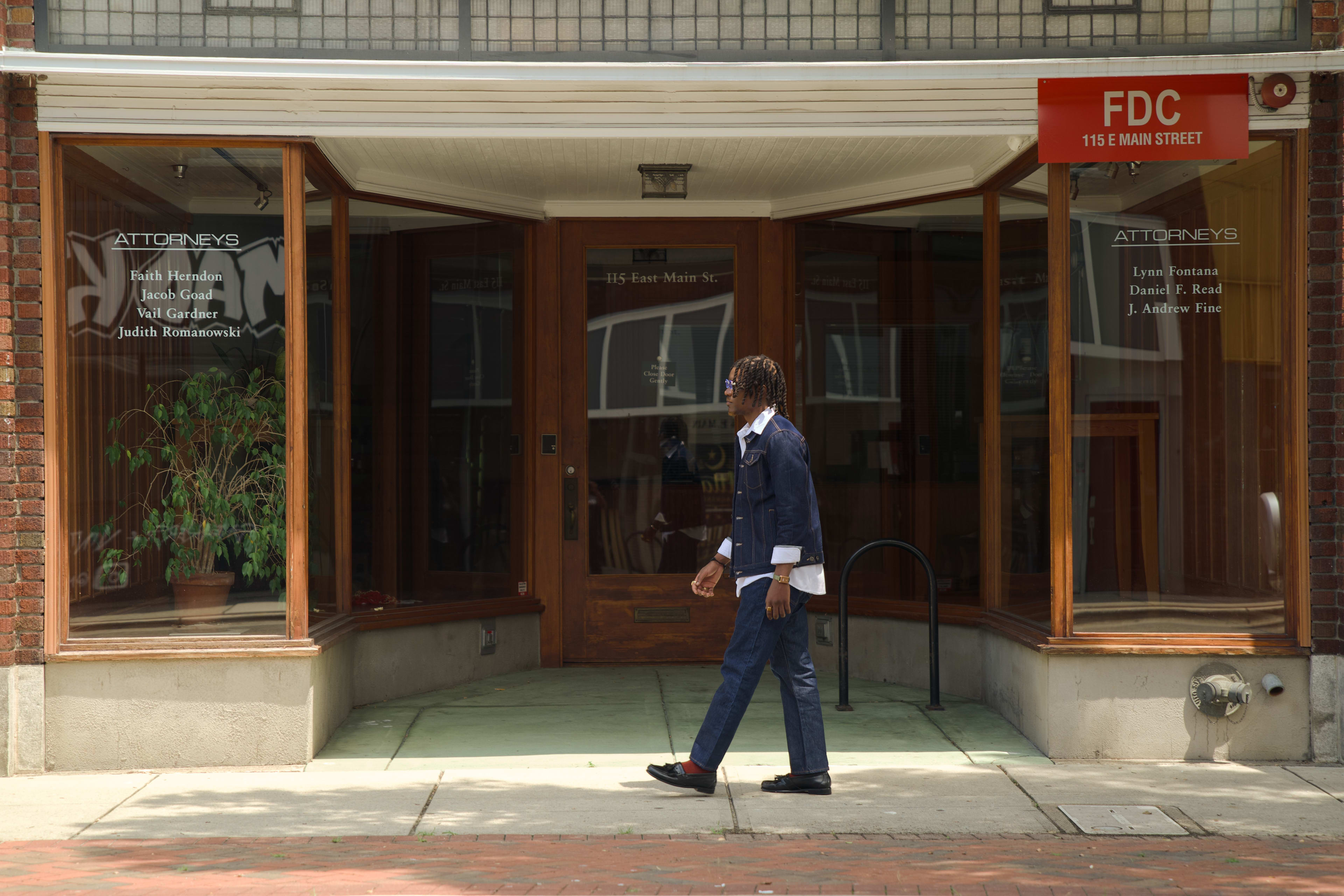 Kama mid-stride past an old wooden storefront on Main Street, full denim