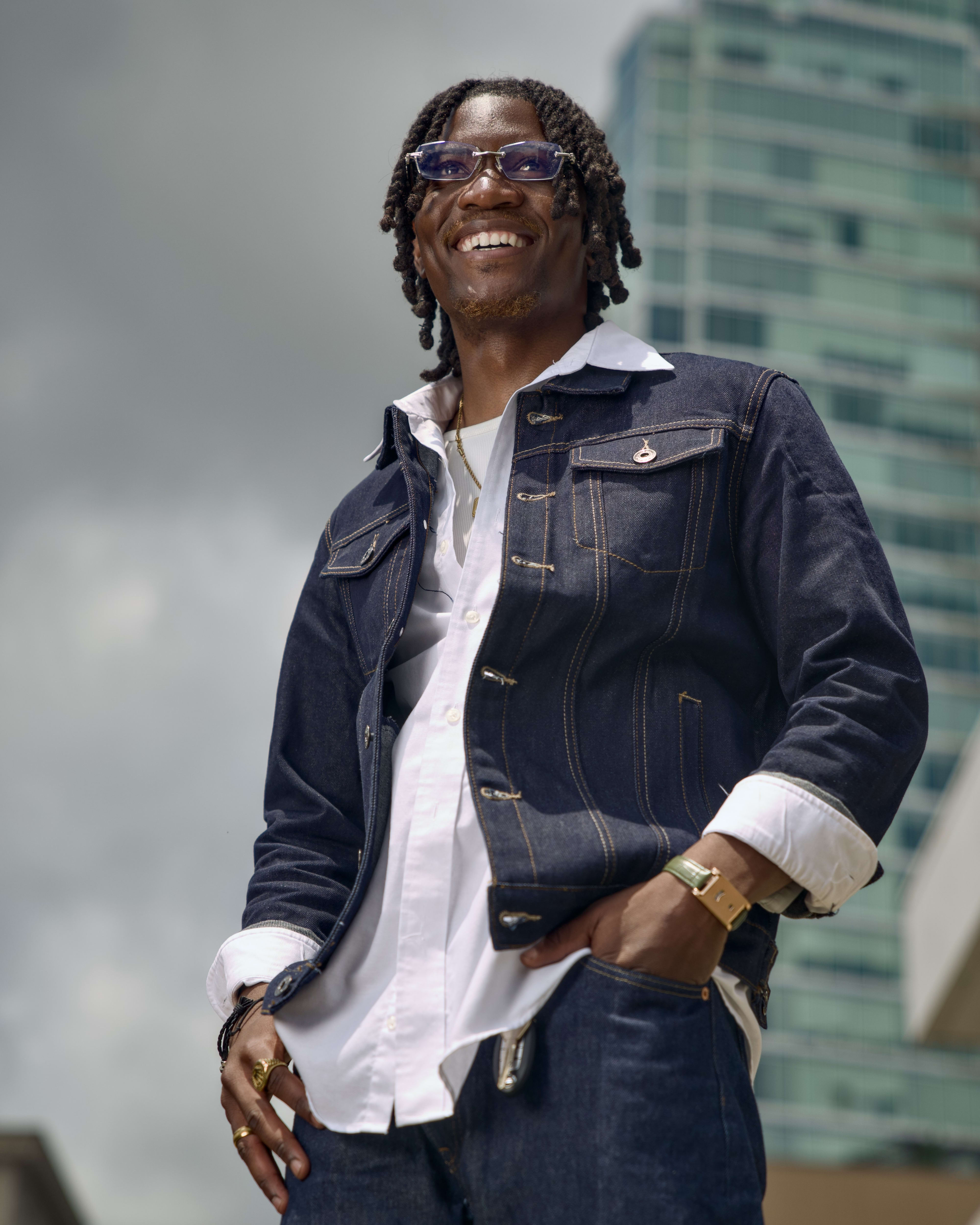 Kama laughing in double denim, glass high-rise fading into the gray sky