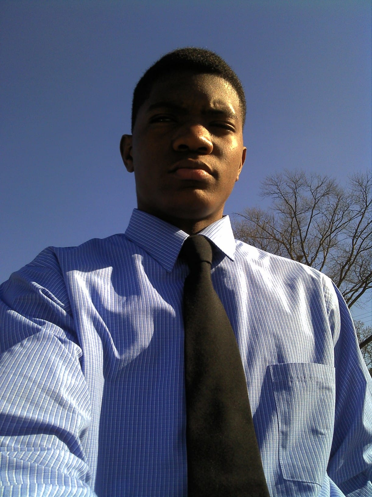 Teenage throwback: young Kama in a blue dress shirt and black tie under a deep blue sky