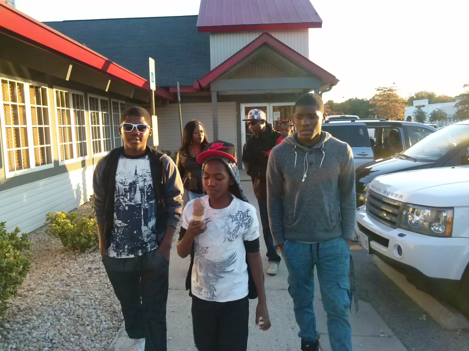 Childhood throwback: three boys walking out of a restaurant at golden hour, ice cream in hand