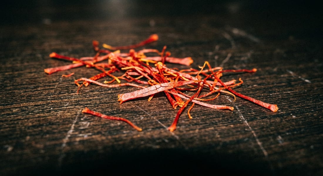 Close-up macro of saffron threads on a dark wooden surface