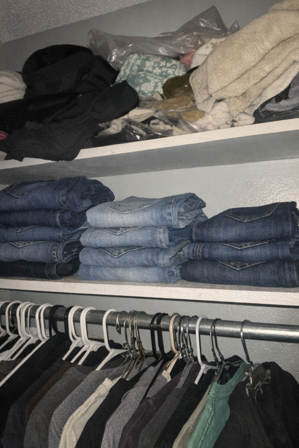 Three sizes of jeans folded in a closet