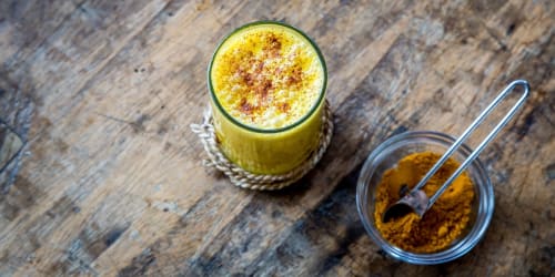 Bicchiere con Golden Milk e vasetto con curcuma