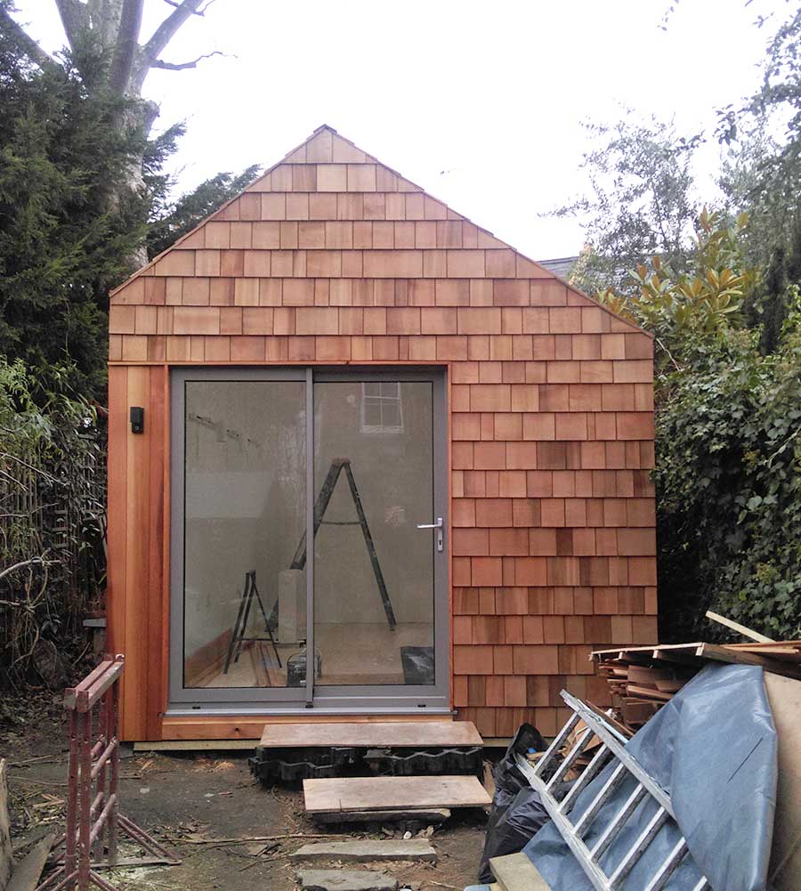 Woodland shed appears in Hackney garden.