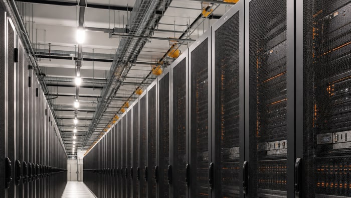 Long rows of enterprise server racks in a large data centre with orange status lights