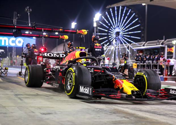 The Red Bull car pulls away from their pit box and crew