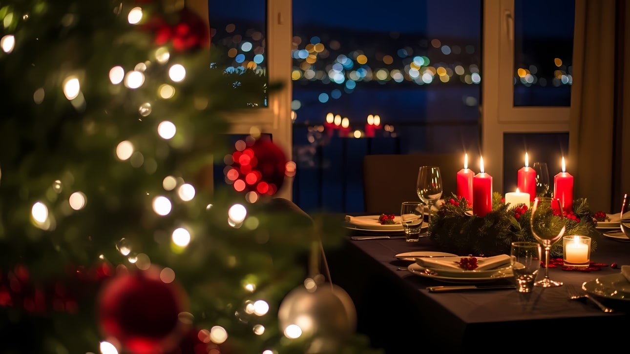 An elegant Christmas dinner table is beautifully set with lit candles, festive decor, and sparkling city lights in the background, creating a war
