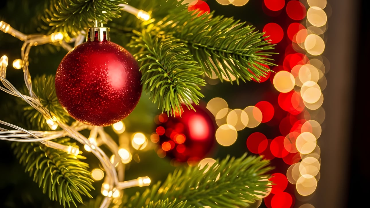 Capture the spirit of the holidays with this festive image of a Christmas tree adorned with sparkling red ornaments and warm, glowing lights.