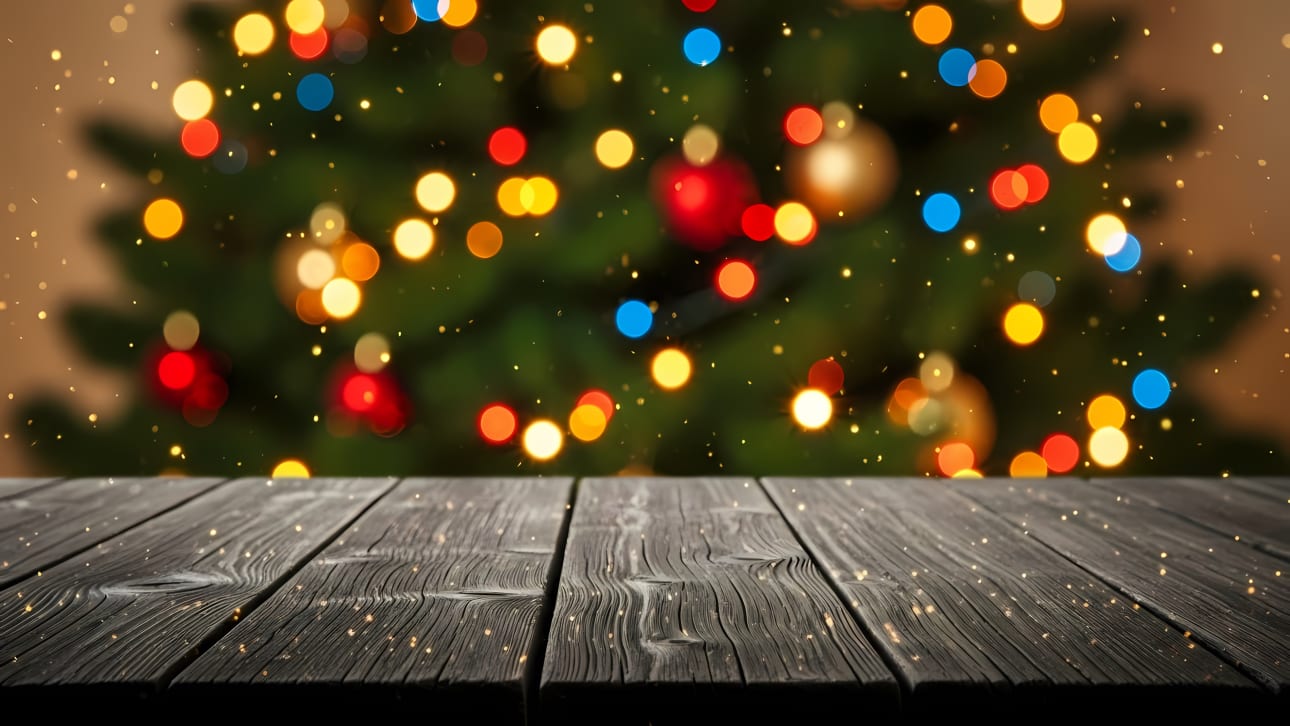 Empty dark wooden table with blurred festive Christmas tree bokeh lights.