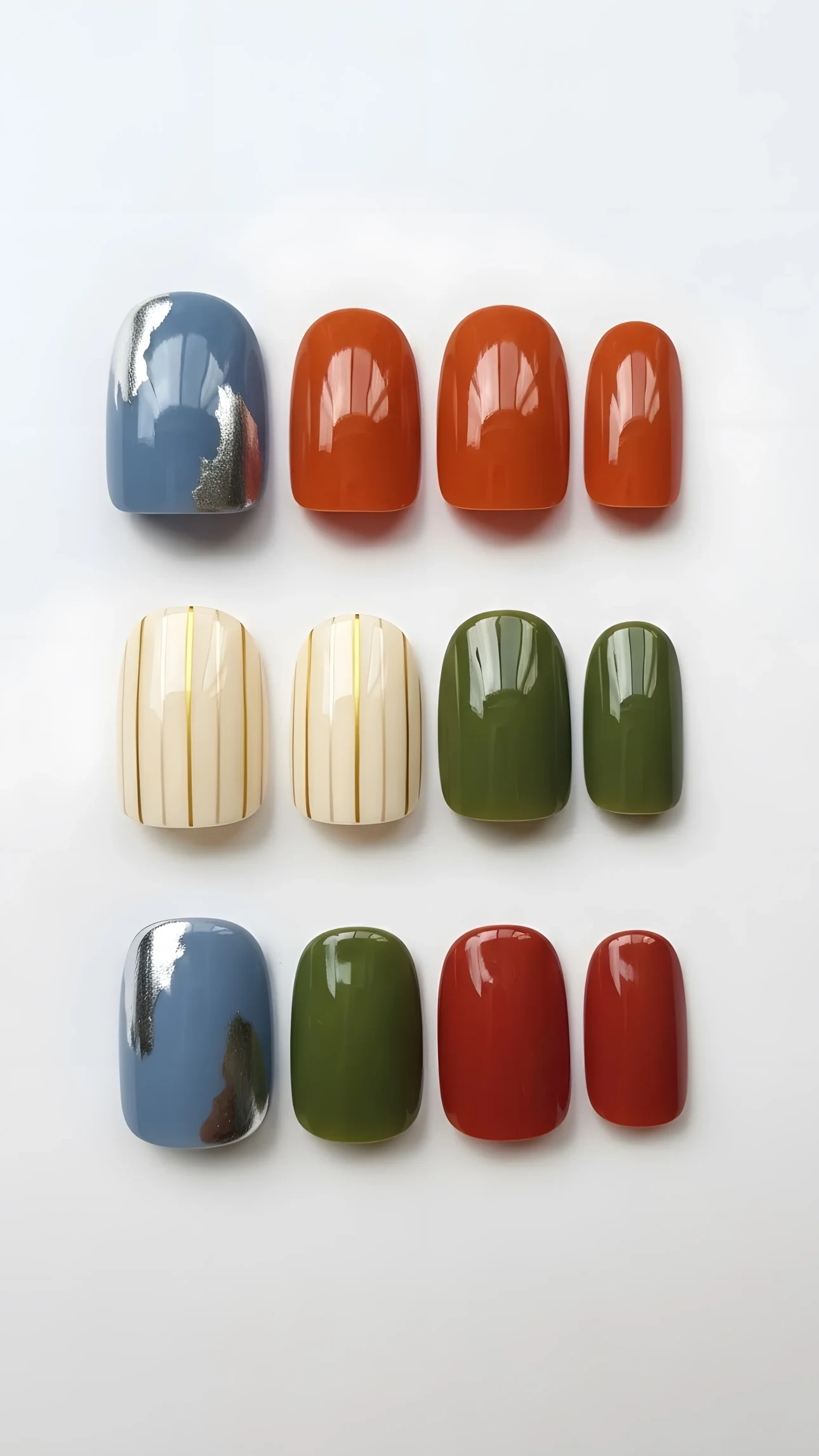 Twelve press-on nails in various colors and designs, including silver foil, stripes, and solid glossy finishes, arranged on white.