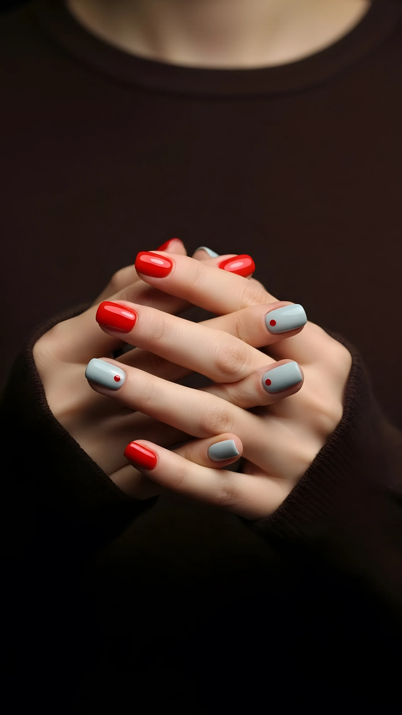 ernates with a muted gray, each gray nail adorned with a small, perfectly placed red dot. The soft, diffused lighting enhances the smooth texture of the skin and the polished finish of the nails, creating a sophisticated and elegant aesthetic. The background is a dark, neutral brown, which serves to further emphasize the hands and their intricate nail design. The overall composition exudes a sense of understated luxury and meticulous attention to detail, making it ideal for projects requiring a touch of refined beauty.