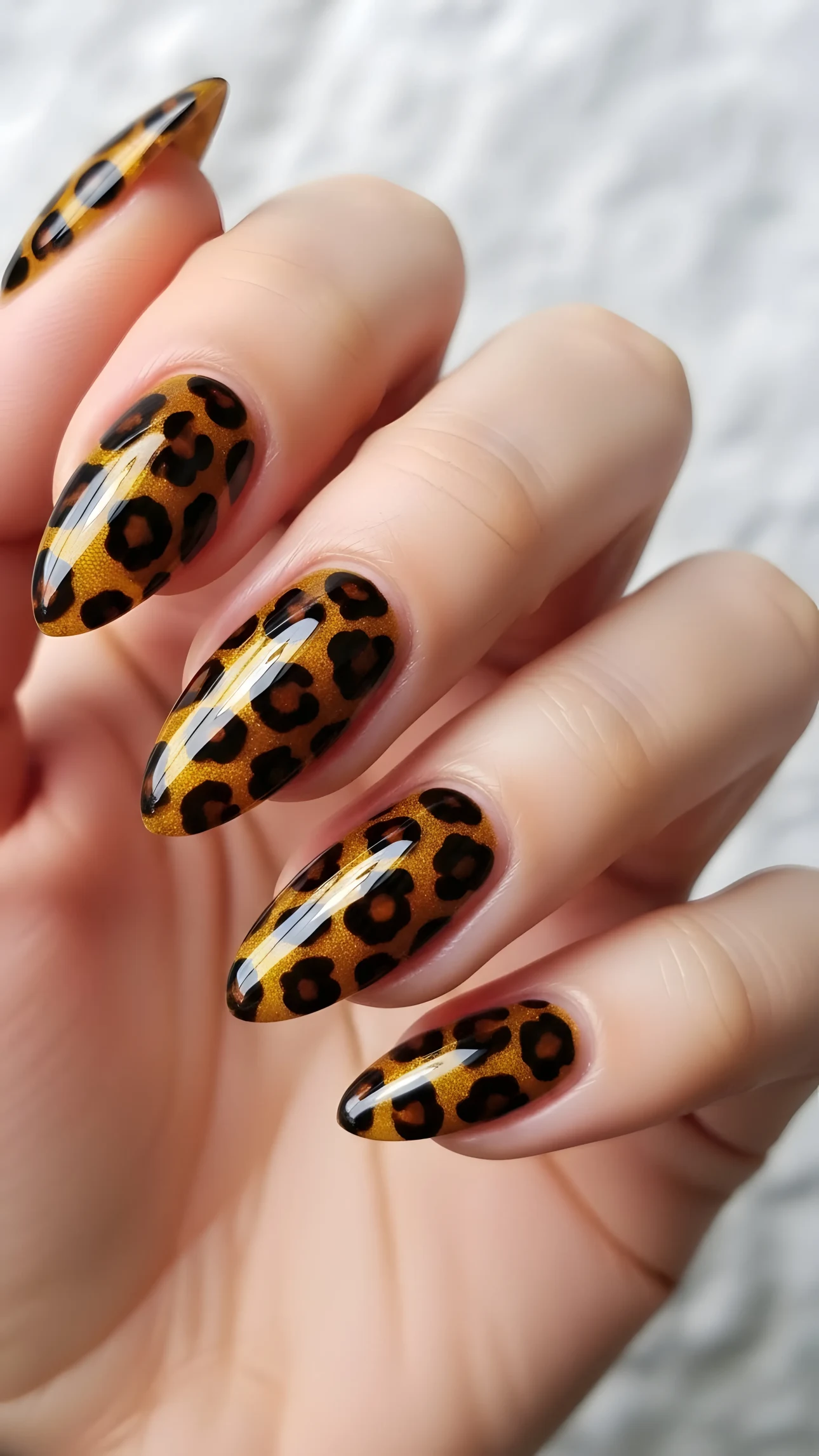 Close-up of almond-shaped nails with golden leopard print design, glossy finish, and warm lighting for beauty and fashion projects.