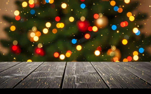 Empty dark wooden table with blurred festive Christmas tree bokeh lights.