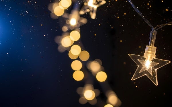 Captivating star string lights and golden bokeh on a dark background, perfect for festive designs.