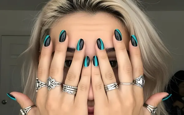 Elevate your designs with this stylish image of a woman showcasing teal and black nail art and silver rings. Perfect for high-fashion and beauty-related projects.