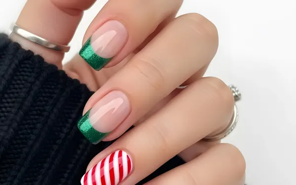 Elevate your designs with this hand featuring a festive green glitter French manicure and a candy cane nail. Perfect for holiday-themed projects.